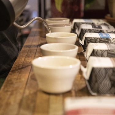 A barista pours hot water into cups for a cupping session.